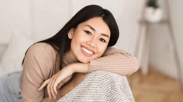 Портрет азіатської дівчини дивлячись на камеру, розслабляючись на дивані — стокове фото