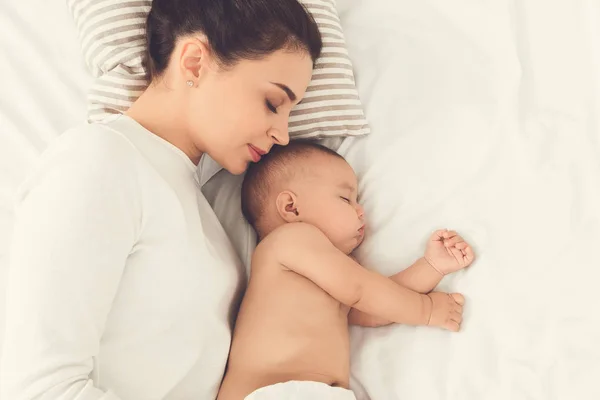 Jovem mãe e seu bebê bonito dormindo na cama — Fotografia de Stock