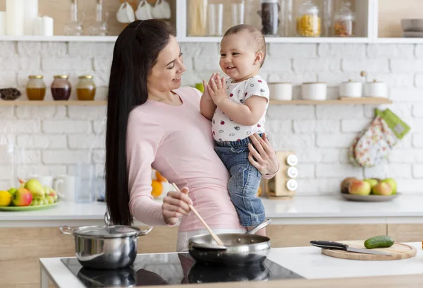 Junge Mutter hält Baby in der Küche in den Armen — Stockfoto