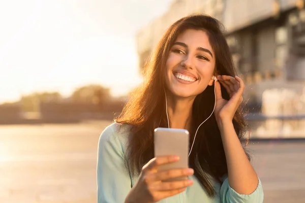 Boa noite. Mulher ouvindo música no telefone, andando ao pôr do sol — Fotografia de Stock