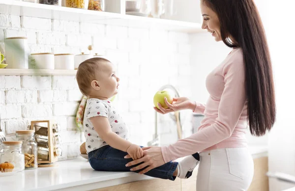 Υπέροχη μητέρα προσφέροντας φρέσκο πράσινο μήλο στο χαριτωμένο μωρό της — Φωτογραφία Αρχείου