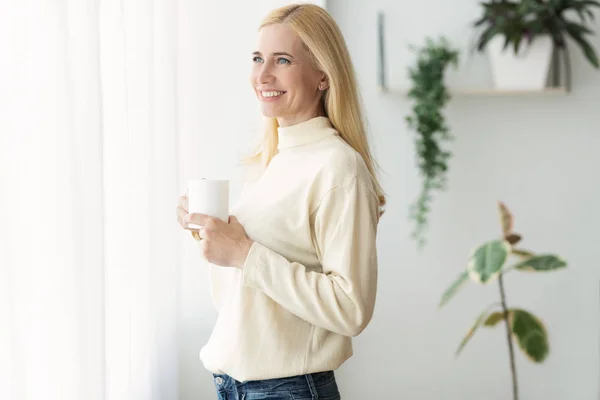 Mature Woman Relaxing At Home With Cup Of Coffee