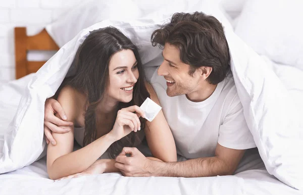 Alegre hombre y mujer milenial sosteniendo condón — Foto de Stock