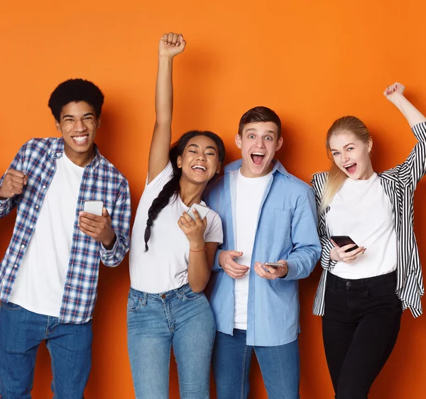 Amigos sortudos. Estudantes com telefones gritando sobre fundo — Fotografia de Stock