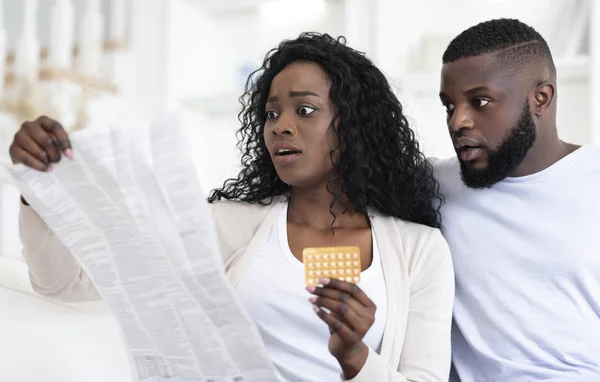 Pareja sorprendida leyendo folleto después de tomar píldoras anticonceptivas — Foto de Stock