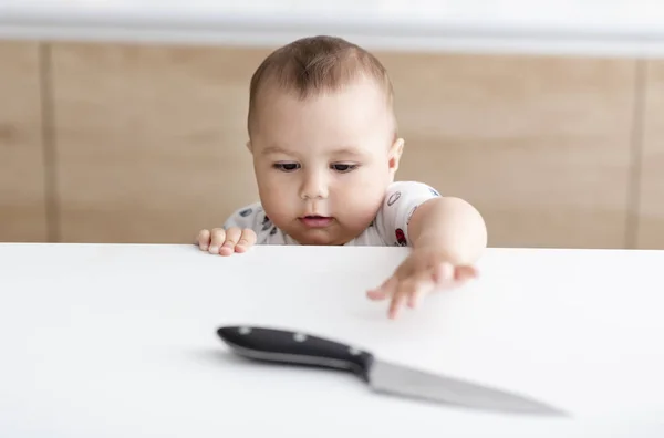 キッチンでの危険な状況。子供はキッチン ナイフを取得しようとしています。 — ストック写真