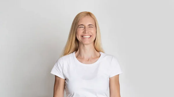 Lykkelig middelaldrende kvinne som smiler med lukkede øyne – stockfoto