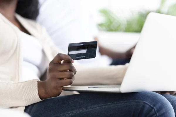 African-american man holding credit card and working on laptop