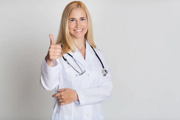 Doktor s Stetoskoborem ukazující palec nahoru přes šedé pozadí — Stock fotografie