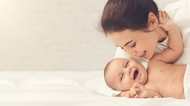 Annesi bebeğini evde yatakta oynarken gıdıklıyor