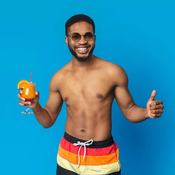 Mutlu Afrikalı adam tropikal kokteyl zevk ve başparmak gösteren — Stok fotoğraf