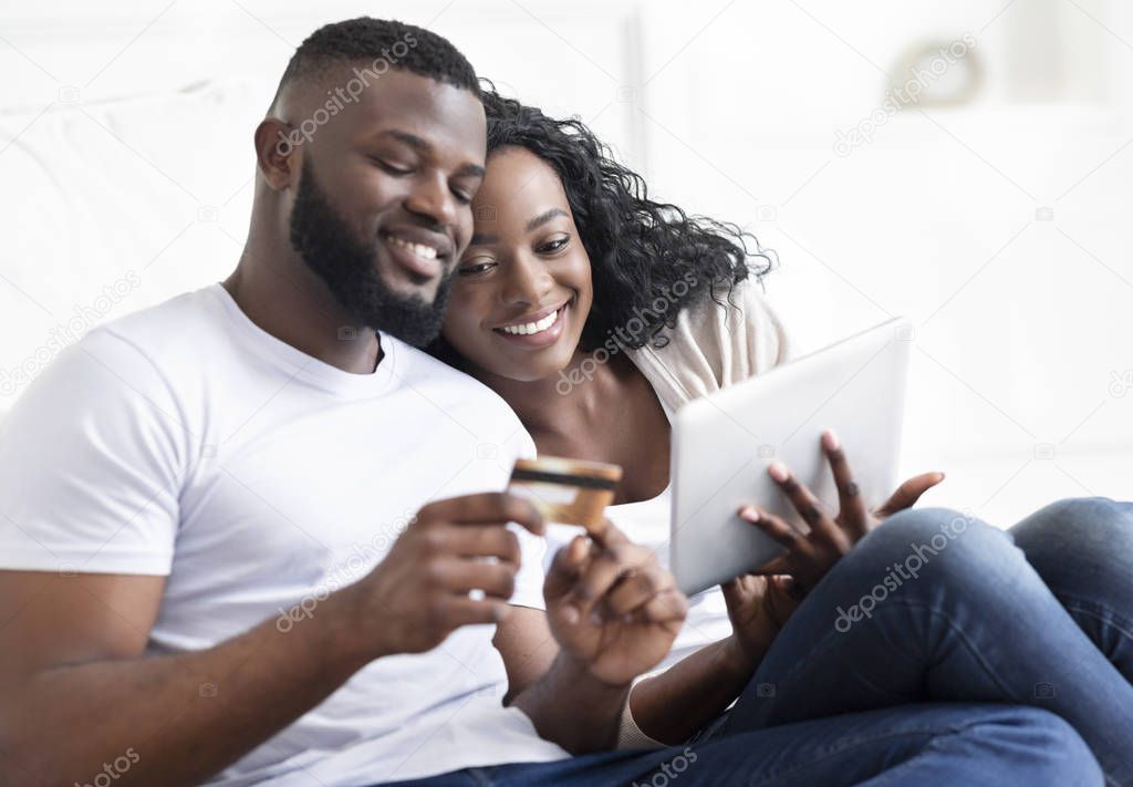Cheerful african couple shopping online on digital tablet