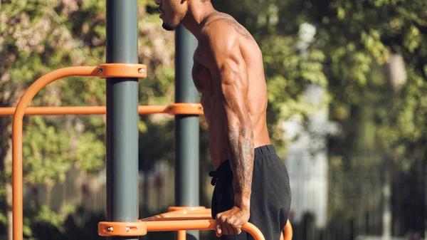 Hombre muscular haciendo caídas de tríceps en barras paralelas — Foto de Stock