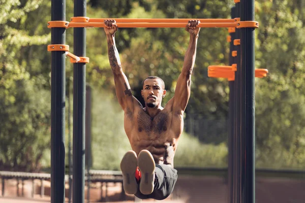 Afro sportovní muž provedení L-SED na vodorovném pruhu — Stock fotografie