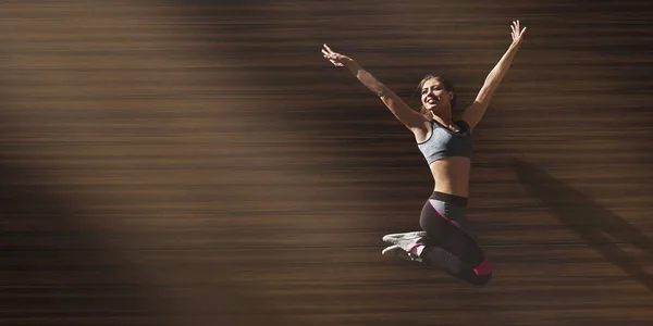 Młoda sportowa dziewczyna skacze szczęśliwie na drewnianym tle zewnątrz — Zdjęcie stockowe