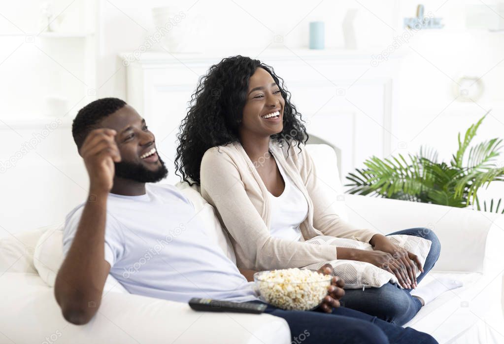 Euphoric teen couple watching tv at home