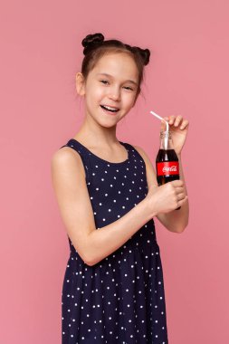 Küçük kız pembe arka plan üzerinde saman ile Coca-Cola Classic içme