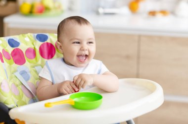 Mutlu bebek mutfakta mama sandalyede oturan