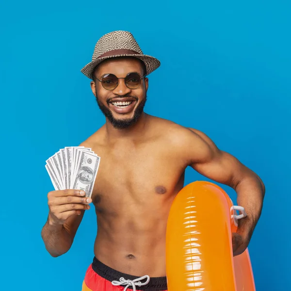 Happy african man holding bunch of money and inflatable ring — Stock Photo, Image