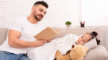Baba uyuyan sevimli kızı için kitap okuyor