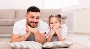 Genç adam yerde sevimli kızıyla yatıyor.