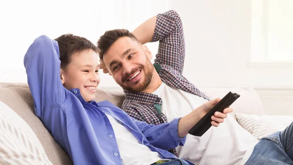 Menino alegre trocando controle remoto, sentado em casa com o pai — Fotografia de Stock