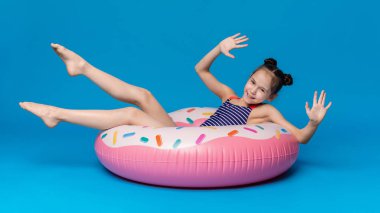 Mutlu küçük kız donut şeklinde pembe şişme halka yüzme