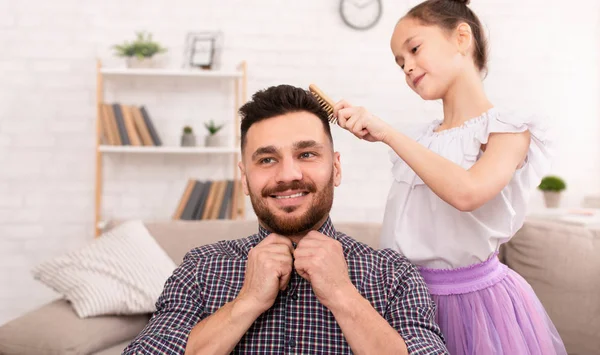 Schattig klein meisje kammen haar knappe vader en glimlachend — Stockfoto