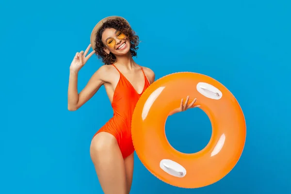 水着を着た陽気な黒人の女の子が水泳の指輪を持ち、平和をジェスチャー — ストック写真