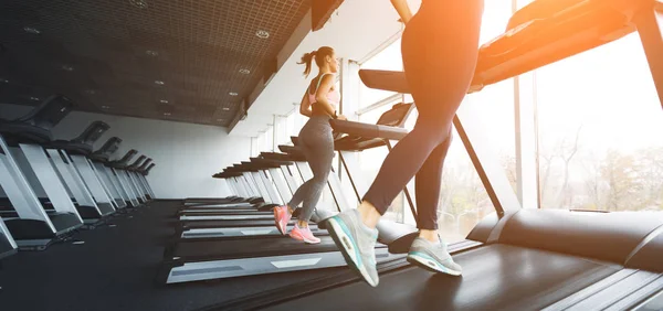 Löpning på löpbandet. Flickor som tränar i gymmet på soliga dagen — Stockfoto