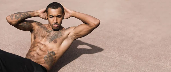 Hombre Afro tatuado haciendo ejercicio Sit Ups en terreno deportivo — Foto de Stock