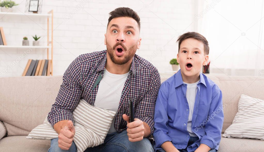 Shocked dad and son watching tv together