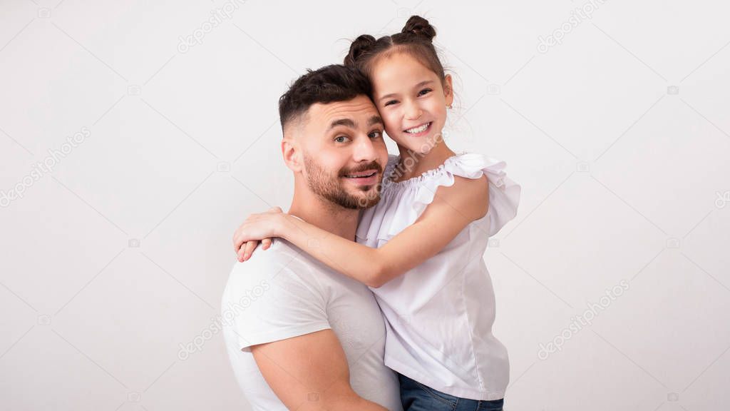 Cheerful father and daughter embracing, studio portrait