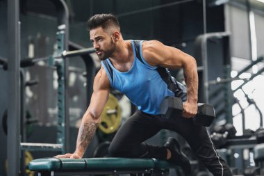 Yakışıklı atlet spor salonunda dumbbell ile çalışıyor