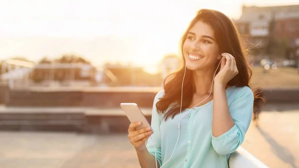 Nő élvezi a zenét fülhallgató, miután séta a városban — Stock Fotó