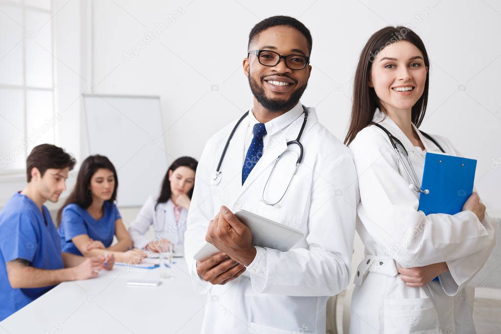 Diverse Professional Doctors In White Coats Posing To Camera At