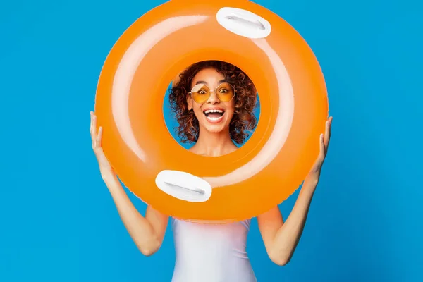 Cheerful black girl smiling through hole in inflatable ring