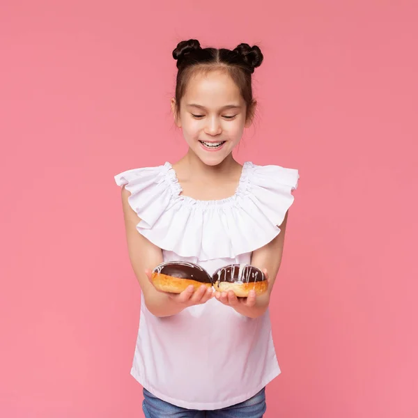 Alegre niña disfrutando de donas cubiertas de chocolate — Foto de Stock