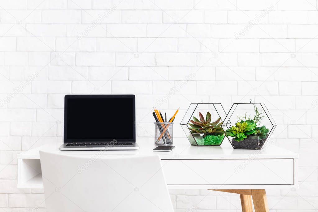 Modern home working place with laptop, and house plants at white brick wall background