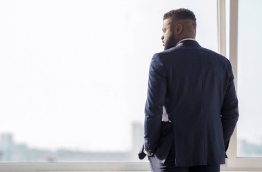 Başarılı Afrikalı işadamı şehir binalarına pencereden bakıyor