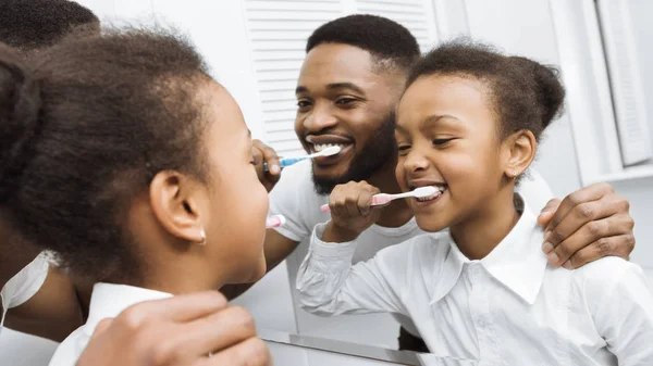 Mała córka i ojciec szczotkowanie zęby razem — Zdjęcie stockowe