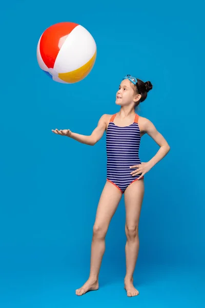 Kleines Mädchen in Badebekleidung spielt mit großem aufblasbaren Ball — Stockfoto