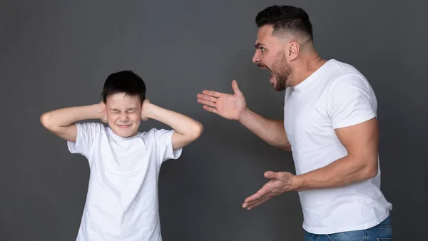 Papá furioso gritándole a su hijo, niño asustado cierra los ojos y los oídos —  Fotos de Stock