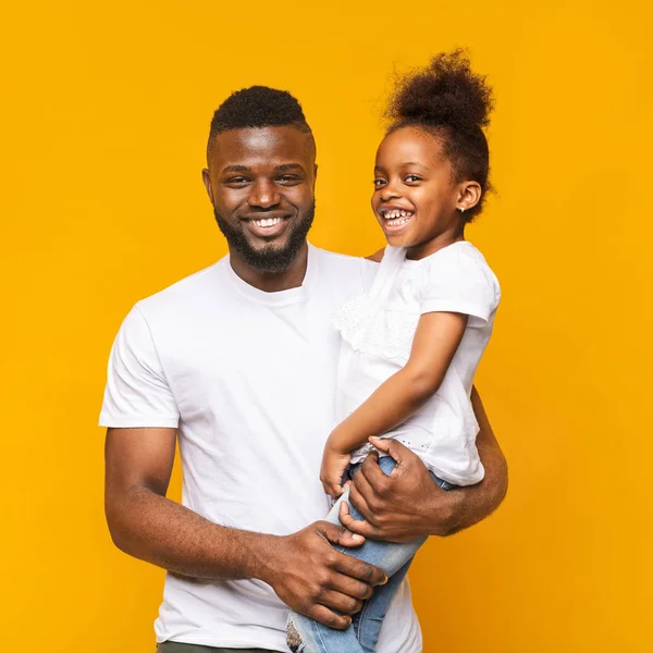 Veselý africký otec držící svou roztomilou dceru na rukou — Stock fotografie