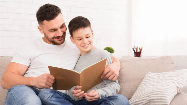 Padre e hijo leyendo el libro, pasando tiempo juntos en casa — Foto de Stock