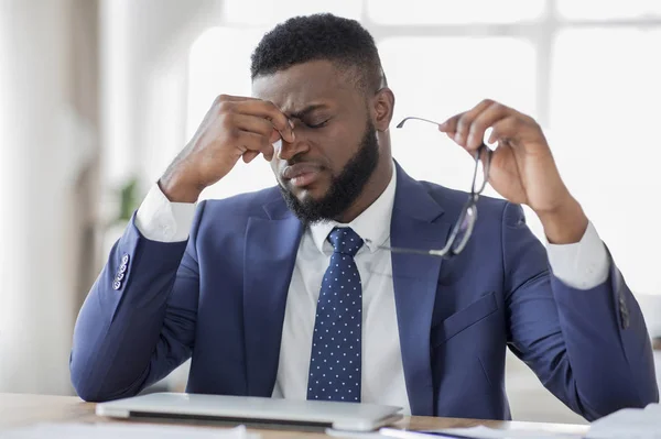 Frustrierter afrikanischer Geschäftsmann massiert sich im Amt die Nase — Stockfoto