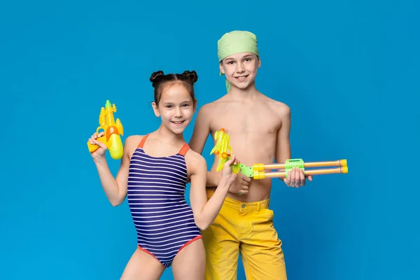 Девочка и мальчик в купальниках с водяными пистолетами — стоковое фото