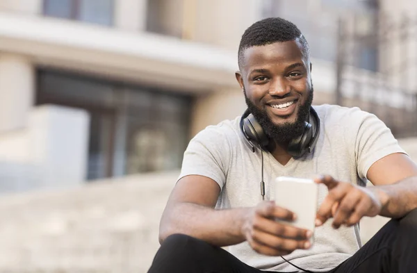 Young african american guy sitting outside with phone — Stock Photo, Image