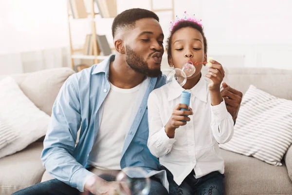 Afro pai e filha soprando bolhas de sabão — Fotografia de Stock