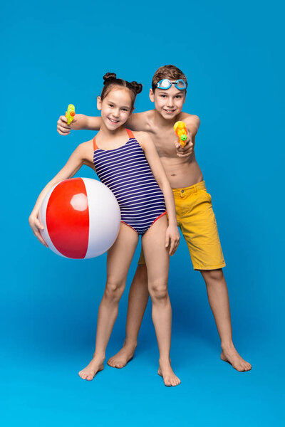 Happy boy and girl in swimwear playing with beach toys